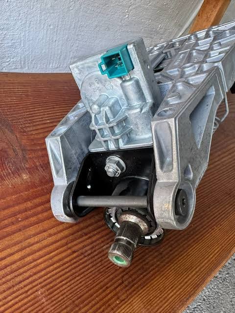 images 23 - Keycode Cork Metal automotive actuator/gear mechanism with a green electrical connector resting on a wooden surface. - images 23